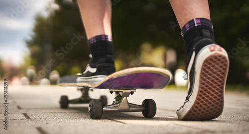 Unrecognizable teenager girl starting skateboarding on a road in a park - Wanderlust and skateboarder outdoor lifestyle concept