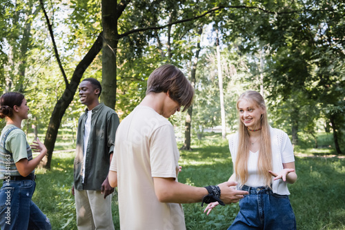 Smiling multiethnic teenagers talking in park during summer © LIGHTFIELD STUDIOS