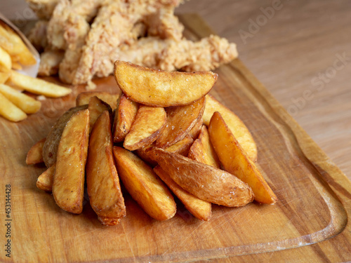 Deep-fried potatoes are lying on a serving board, side view