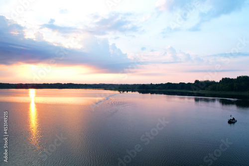 Fishermen in a boat fishing in the lake. Fishing for river fish from a motor boat using a fishing rod or spinning rod. Sports fishing on the water. Rest in the wild on sunset, aerial view