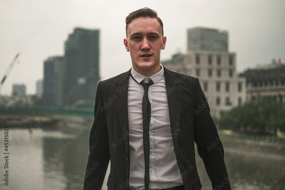 Portrait of attractive caucasian young businessman in black formal suit outdoors in the big city. Looking at camera with copy space. Serious man. Portrait of attractive caucasian young businessman in black formal suit outdoors in the big city. Looking at camera with copy space. Serious man.