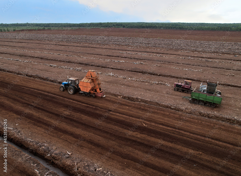 Peat extraction site. Harvester at collecting peat on peatlands. Mining and harvesting peatland