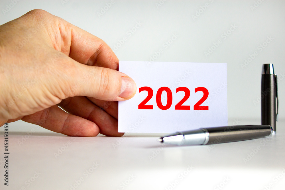 2022 happy new year symbol. Businessman holds white card with number 2022. Metallic pen. Beautiful white background, copy space. Business and 2022 happy new year concept. 2022 happy new year symbol. Businessman holds white card with number 2022. Metallic pen. Beautiful white background, copy space. Business and 2022 happy new year concept.
