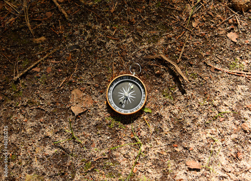 Compass on groud in the forest. Tourist compass for orientation on the terrain. Magnetic declination сalculator. Map reading and land navigation concept. Orient on maps
