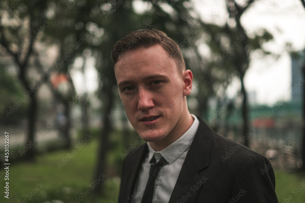 Close-up portrait of handsome caucasian young man in black formal suit with the tie outdoors. Looking at camera with copy space. Close-up portrait of handsome caucasian young man in black formal suit with the tie outdoors. Looking at camera with copy space.