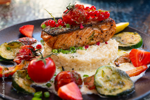 Delicious risotto with baked grilled salmon steak with berries and vegetables. Mediterranean cuisine, healthy food