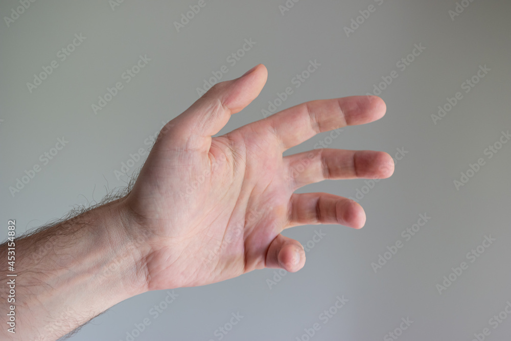 Caucasian male hand making generic gesture. Close up shot, opened palm, isolated on gray background