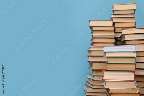Many hardcover books on turquoise background, space for text. Library material photo