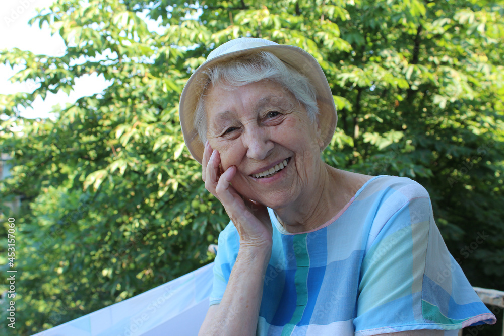 Positive senior woman watering decorative plants on balcony Positive senior woman watering decorative plants on balcony