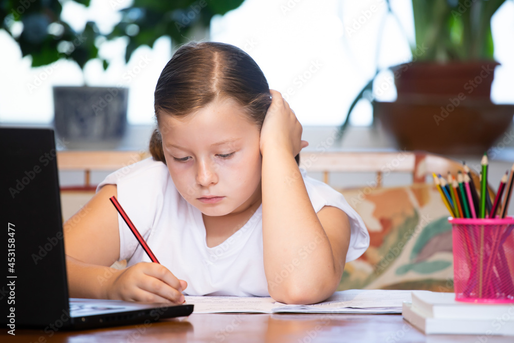 Study online with video call teacher. Young girl learn online and looking at laptop at home.Social distancing. Study online with video call teacher. Young girl learn online and looking at laptop at home.Social distancing.