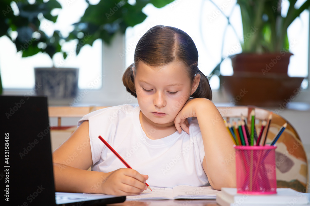 Study online with video call teacher. Young girl learn online and looking at laptop at home.Social distancing. Study online with video call teacher. Young girl learn online and looking at laptop at home.Social distancing.