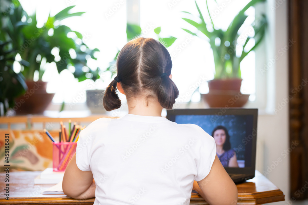 Study online with video call teacher. Young girl learn online and looking at laptop at home.Social distancing. Study online with video call teacher. Young girl learn online and looking at laptop at home.Social distancing.