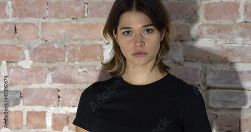 A closeup view of a woman with short hair and a black shirt frowning then smiling in 4k photo