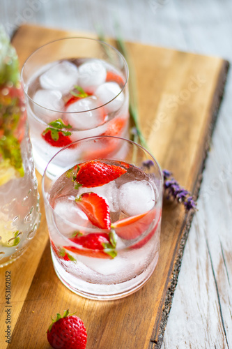 Fresh fruit summer drink with strawberry, lime and ice placed on wooden desk