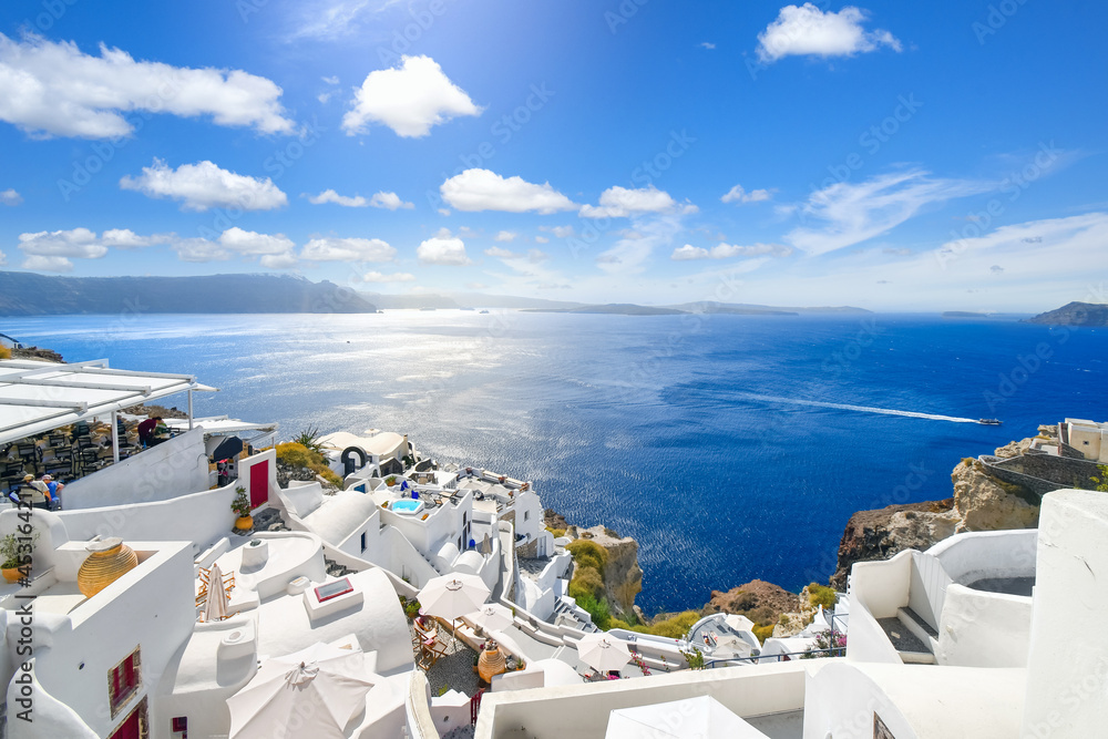The whitewashed hillside town of Oia, Greece, filled with cafes and hotels overlooking the Aegean Sea and Caldera. - obrazy, fototapety, plakaty 