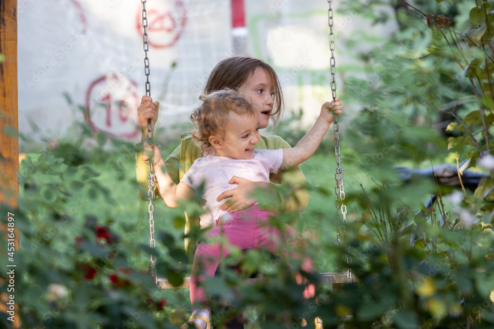 Girls sitting in a swing and laughing and enjoying Girls sitting in a swing and laughing and enjoying