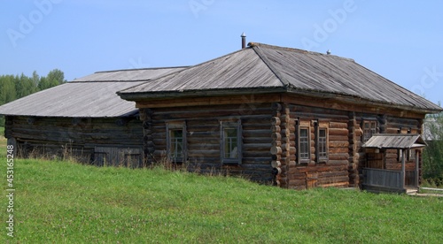 Wooden rural old house made of logs. Wooden house made of logs, green grass, blue sky. 