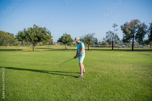 male golf player on professional golf course. portrait of golfer in cap with golf club.