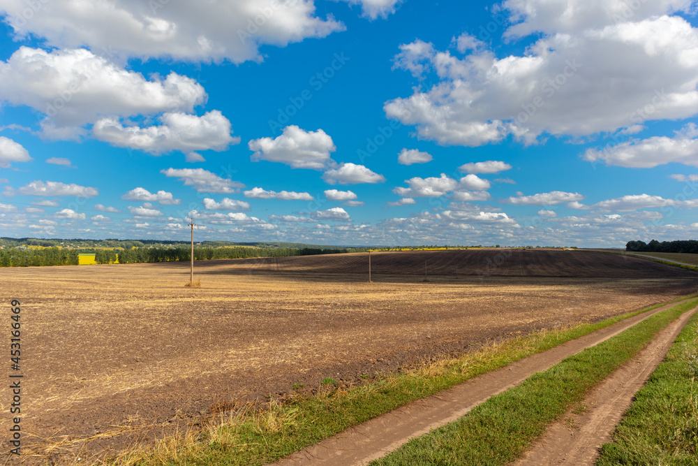 a harvested and plowed field under a cloudy sky a harvested and plowed field under a cloudy sky
