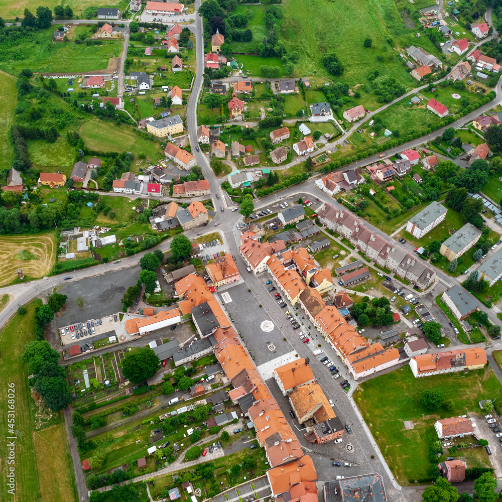 Aerial photo of a typical Polish hosing estate in the mountains towns, taken on a sunny part cloudy day using a drone, showing the housing estate and farmers fields.