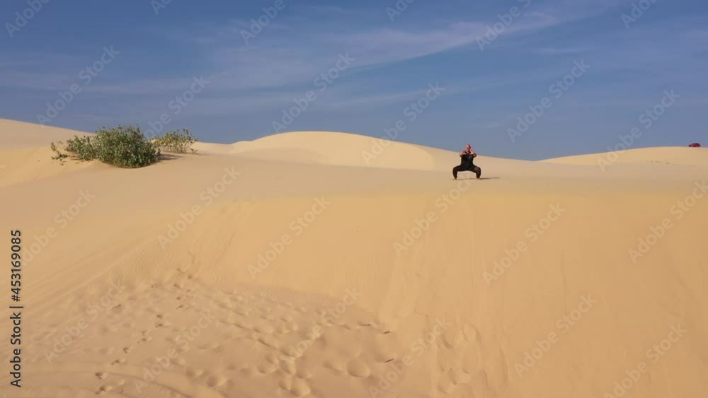 Old man in black is engaged in kung fu in the dunes at sunset. a lot of sand, golden sunset light. sports training. handsome man meditating. Aerial view to desert with sensei kung fu training Old man in black is engaged in kung fu in the dunes at sunset. a lot of sand, golden sunset light. sports training. handsome man meditating. Aerial view to desert with sensei kung fu training