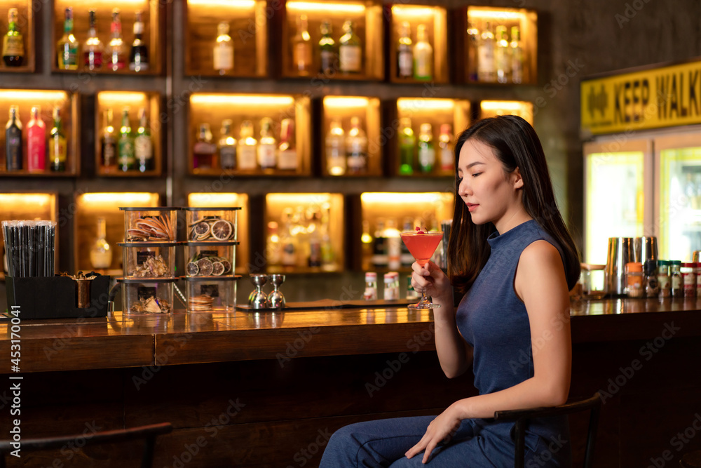 Beautiful woman is drinking cocktail and having enjoy to relaxing while sitting alone to listening music Beautiful woman is drinking cocktail and having enjoy to relaxing while sitting alone to listening music