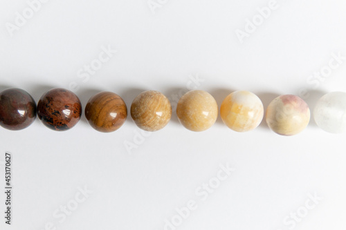  Large collection of beautiful stones. polished precious round stones from dark to light on a white background. Geologist exposition. Small planets.