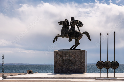 A silhouette of a statue of Alexander the Great galloping on a horse mounted on a cubic marble pedestal on the Thessaloniki seafront in backlight