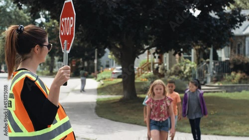 A crossing guard helps children across the street while walking to school