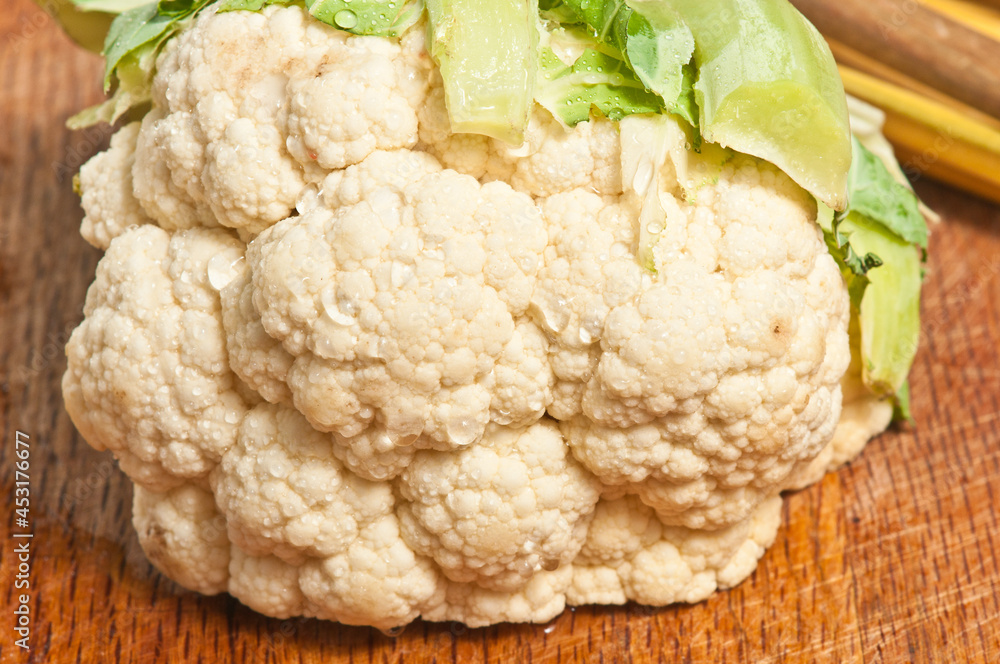 top view, close up of a head of cauliflower with leaves removed, on a wood cutting board top view, close up of a head of cauliflower with leaves removed, on a wood cutting board