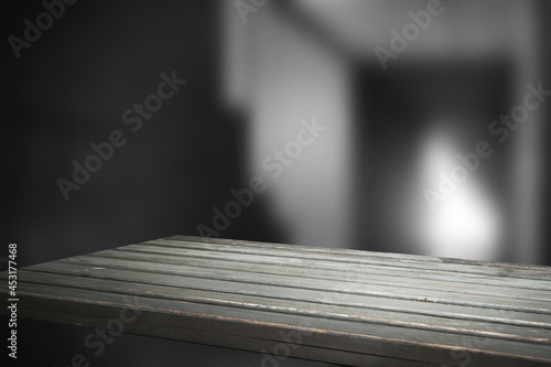 empty wooden table on the background of an empty dark wall, with focal light, for the montage of your project