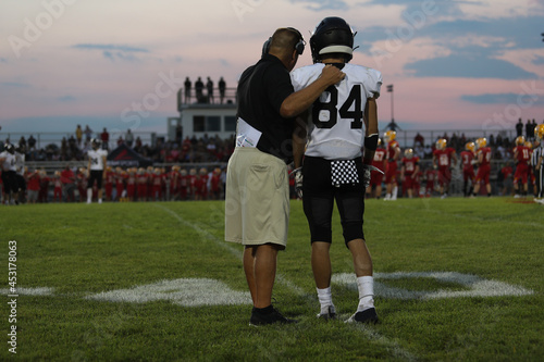 Photo A high school football coach talks to a player