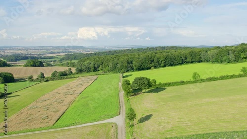 Up moving drone shot of a beautiful summer landscape with hills, meadows and aforest. Agricultural terrain and countryside in Lower Saxony, Germany. photo