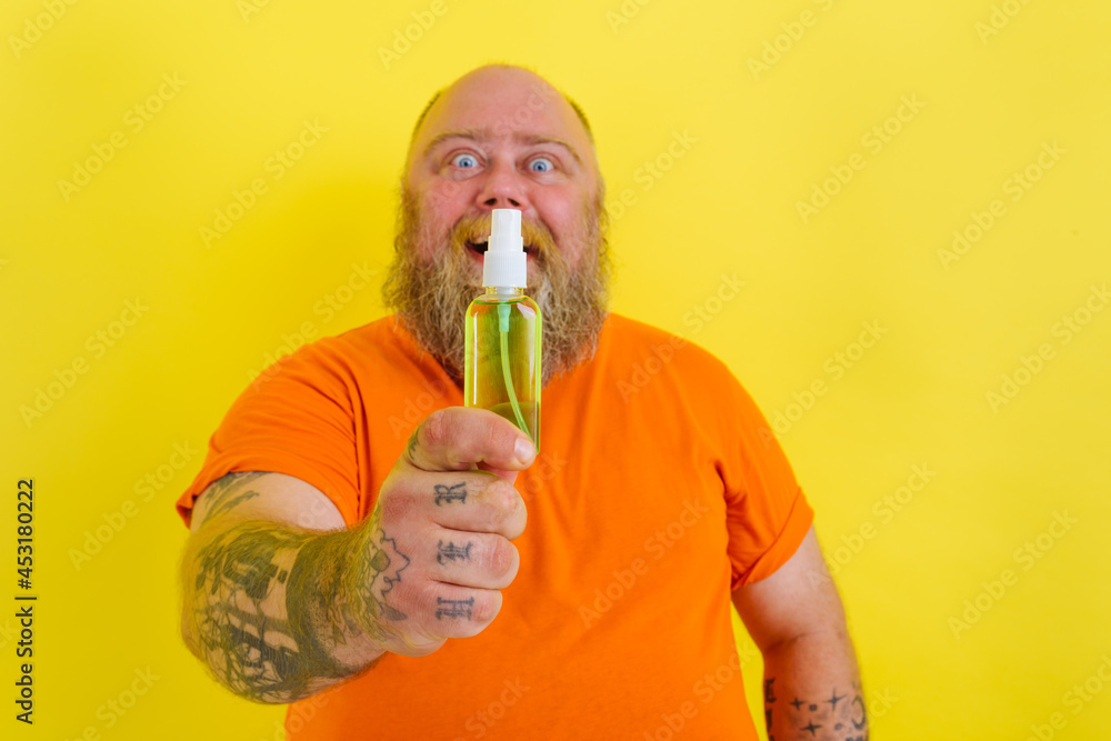 Happy man with beard and tattoos holds a hands cleaner against covid19 Happy man with beard and tattoos holds a hands cleaner against covid19