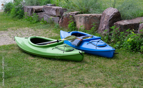 Green and blue kayaks on the grass beside a lake
