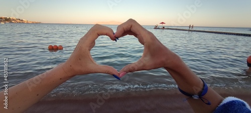 two hands in the shape of a heart on the background of the sea