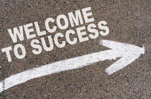 On the asphalt road markings an arrow with the inscription - WELCOME TO SUCCESS © Dzmitry