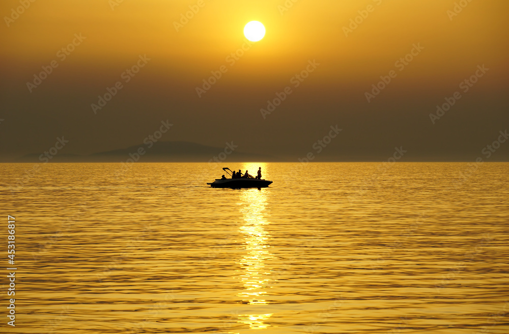 Silhouette of a ship with people sailing the sea at dusk sunset