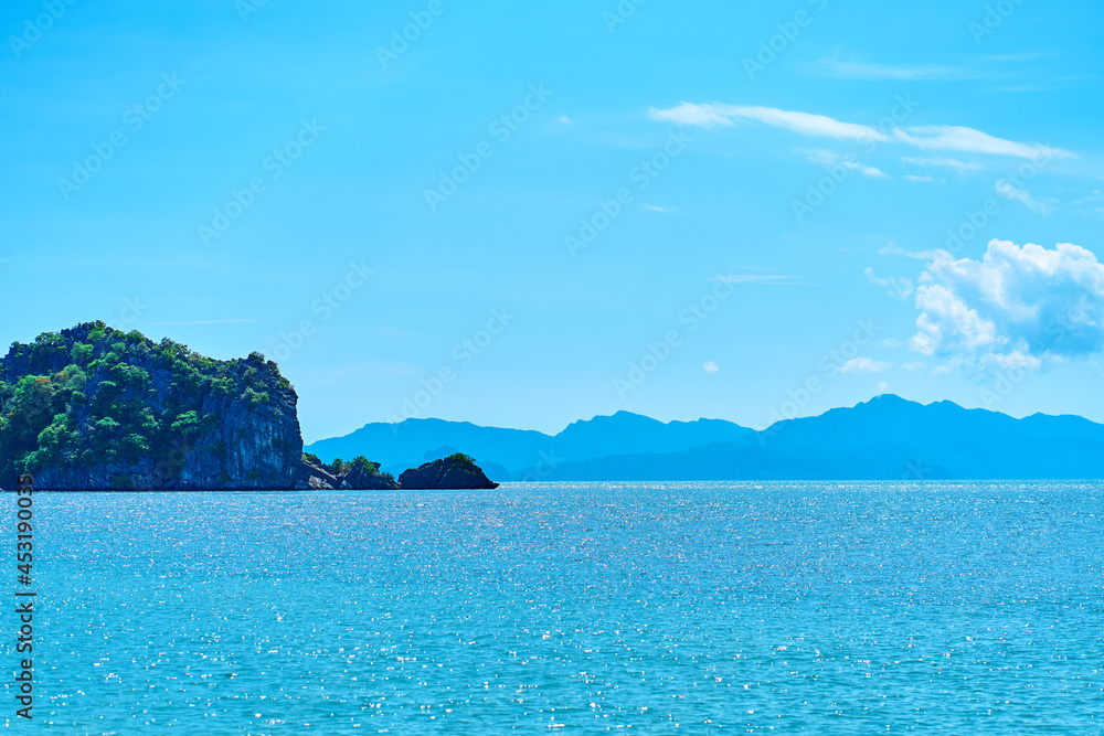 Fototapeta premium View from the beach to the rocks in the ocean away from the coast. Natural landscape of a tropical beach