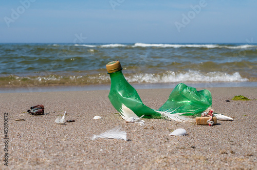 Garbage on the beach. Plastic on the beach. Pollution of the coast with plastic bottles. Green empty bottle.