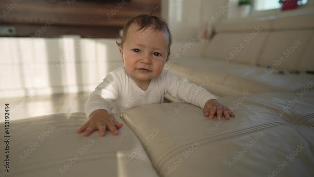 Cute baby toddler leaning on sofa learning to stand up. Adorable infant child learning to stand holding into couch. High quality 4k footage Cute baby toddler leaning on sofa learning to stand up. Adorable infant child learning to stand holding into couch. High quality 4k footage