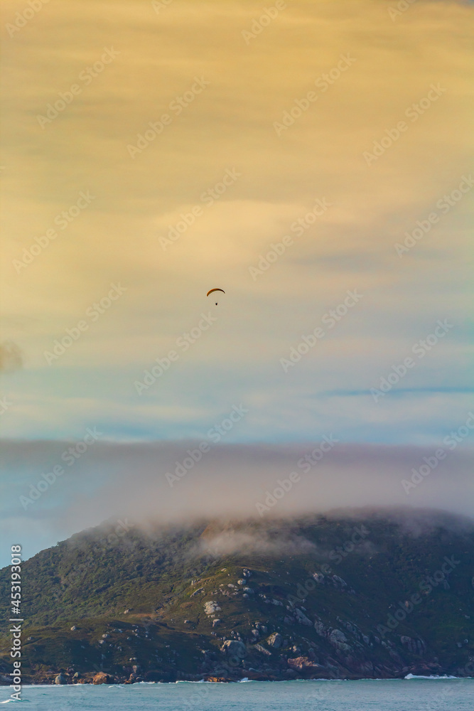 paragliding on the sea, extreme sport, paraglider flying at sunset at Praia dos Ingleses and Santinho, in the city of Florianópolis, Brasil