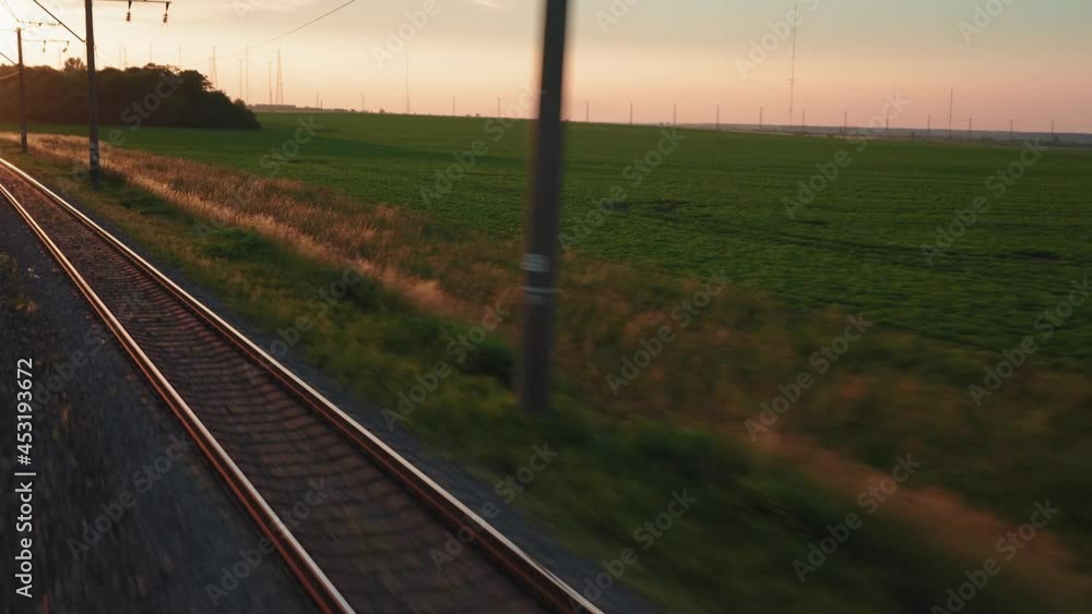 view from window high-speed train on landscape of beautiful nature wild field and forest railroad tracks rails on evening sunset in summer background. Transport, travel, railway, communication concept view from window high-speed train on landscape of beautiful nature wild field and forest railroad tracks rails on evening sunset in summer background. Transport, travel, railway, communication concept