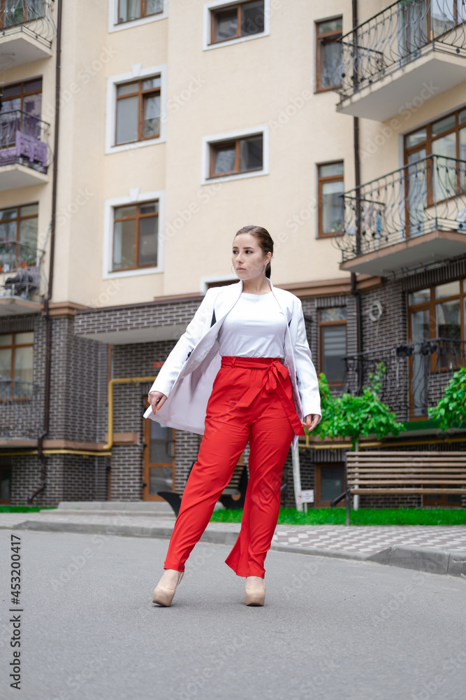 business woman in red pants, white blouse and jacket walking by the street business woman in red pants, white blouse and jacket walking by the street