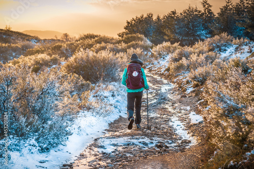 Girl Pilgrim Hiker on the Snow Winter Mountain Forest Evening on the Way of St James Pilgrimage Trail Camino de Santiago outside El Acebo at Sunset
