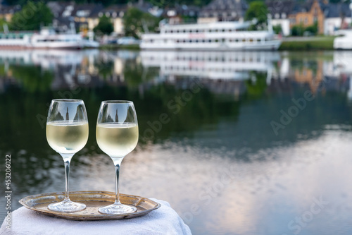 Tasting of white quality riesling wine served on outdoor terrace in Mosel wine region with Mosel river and old German town on background, Germany photo