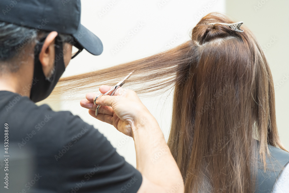 Fototapeta premium ヘアサロンで女性の髪の毛をカットするスタイリストの手元