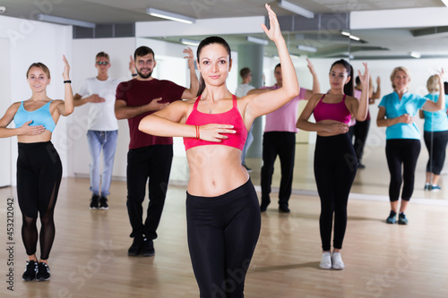 Group of active people training dance together in fitness studio