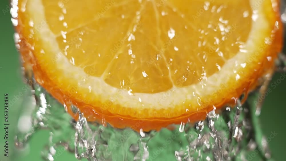 Water splashing on fresh orange in slow motion. Water dropping from citrus fruit. Close up orange slice rich in vitamin C. Water splashing on fresh orange in slow motion. Water dropping from citrus fruit. Close up orange slice rich in vitamin C.