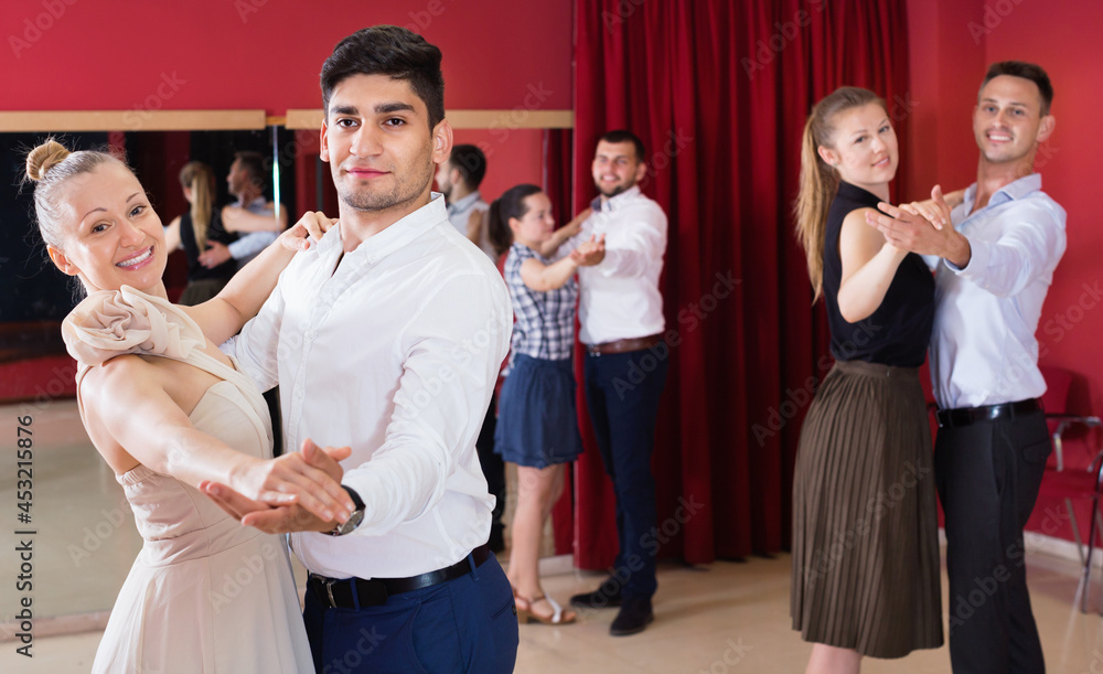 Happy people learning to dance waltz in dancing class